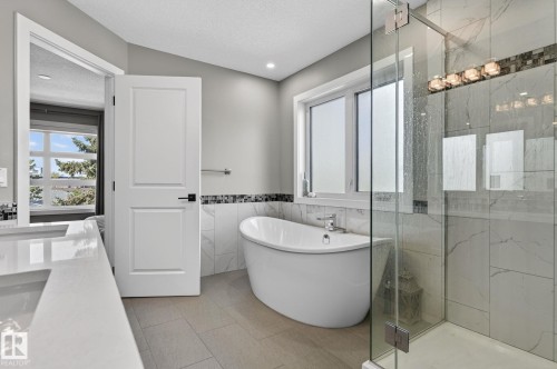 Contemporary bathroom featuring a freestanding soaking tub, glass-enclosed shower, wood-finish flooring, and a window with privacy glass - 8809 148 Street, Edmonton, AB - Indoor Photo Showing Bathroom