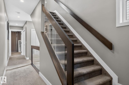 Contemporary staircase featuring glass railing and dark wood-finish handrails - 8809 148 Street, Edmonton, AB - Indoor Photo Showing Other Room