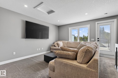Carpeted living space with recessed lighting, a mounted flat-screen television, and expansive windows - 8809 148 Street, Edmonton, AB - Indoor Photo Showing Living Room
