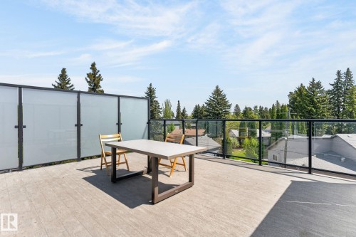 Expansive rooftop deck featuring a concrete surface, glass railing, and frosted privacy screening - 8809 148 Street, Edmonton, AB - Outdoor