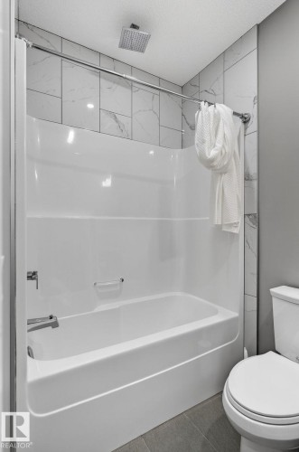 Bathtub-shower combination featuring a white surround and a ceiling-mounted rainfall showerhead - 8809 148 Street, Edmonton, AB - Indoor Photo Showing Bathroom