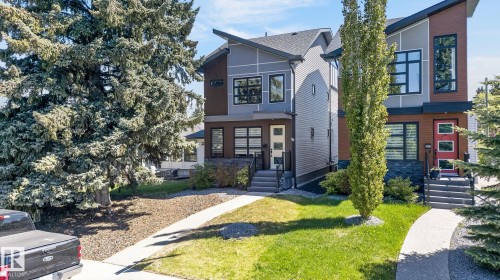 Modern architectural design featuring multi-toned siding, a distinct roofline, numerous windows with dark frames, and a front walkway leading to the entrance - 8809 148 Street, Edmonton, AB - Outdoor With Facade