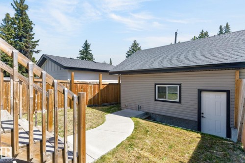 Rear exterior featuring gray siding, a white service door with black trim, and a sliding window - 8809 148 Street, Edmonton, AB - Outdoor With Exterior