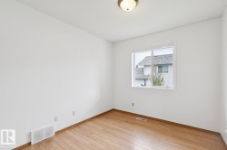 Room featuring wood-finish flooring, white baseboards, and a white window frame - 