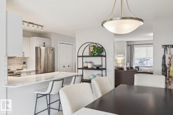 Bright kitchen featuring white cabinetry, stainless steel appliances, a subway tile backsplash, and a breakfast bar with stone-finish countertops - 