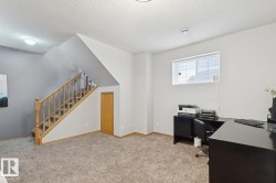 Carpeted interior space featuring a wooden staircase with balusters, a built-in wooden door, and a window with blinds - 