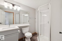 Bathroom featuring a white vanity with integrated sink, rectangular mirror, and contemporary four-light fixture - 