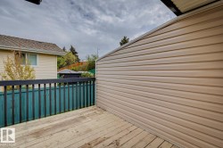 Wooden deck with a dark railing and green fence - 