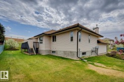 Expansive backyard featuring a manicured lawn, a two-level deck with dark wood-finish railings, and mature landscaping - 