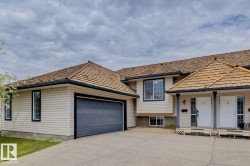 Duplex exterior featuring light beige siding, a two-car garage with a gray door, and a cedar shake roof - 
