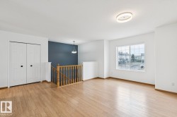 Expansive room featuring wood-finish flooring, a large window with grid panes, and a modern ceiling light fixture - 