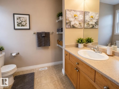Vanity featuring wood-finish cabinetry, a white oval undermount sink, and a speckled light-toned countertop - 102 Hartwick Loop, Spruce Grove, AB 