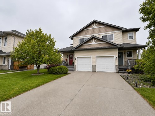 Two-story duplex with light-colored siding, a dual garage, and a concrete driveway - 102 Hartwick Loop, Spruce Grove, AB 