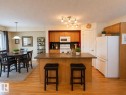 Kitchen island with integrated sink and seating for two, wood-finish flooring, and track lighting - 102 Hartwick Loop, Spruce Grove, AB 