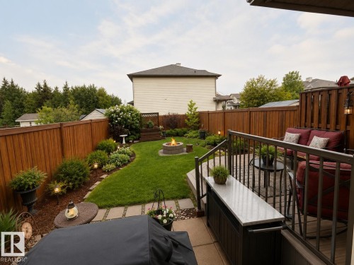Expansive backyard featuring a stone-lined fire pit, manicured lawn, and mature perimeter landscaping - 102 Hartwick Loop, Spruce Grove, AB 
