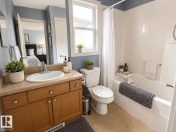 Bathroom with light wood-finish vanity, oval undermount sink, and light speckled countertop - 