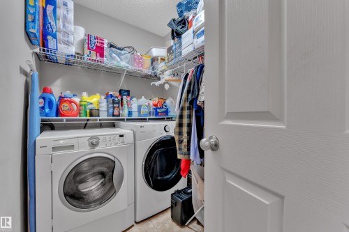 Dedicated laundry area featuring a white front-load washer and dryer, wire shelving, and neutral wall paint - 14031 136 Street, Edmonton, AB 