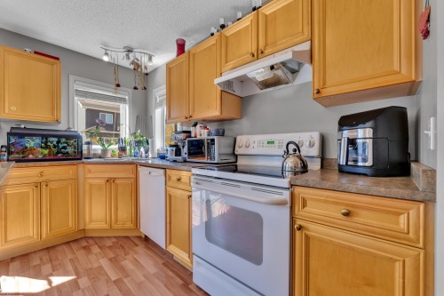 Kitchen featuring wood-finish flooring, light wood cabinetry, white appliances, and laminate countertops - 14031 136 Street, Edmonton, AB 