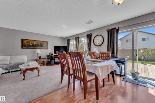 Open-concept living and dining areas featuring wood-finish flooring in the dining space and plush carpeting in the living area - 14031 136 Street, Edmonton, AB 