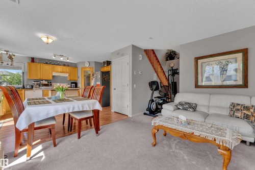 Open-concept living area featuring light gray carpeting, wood-finish flooring, and a kitchen with warm-toned cabinetry - 14031 136 Street, Edmonton, AB 