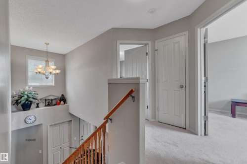 Upper-level landing featuring a chandelier, window, and light gray wall paint - 14031 136 Street, Edmonton, AB 