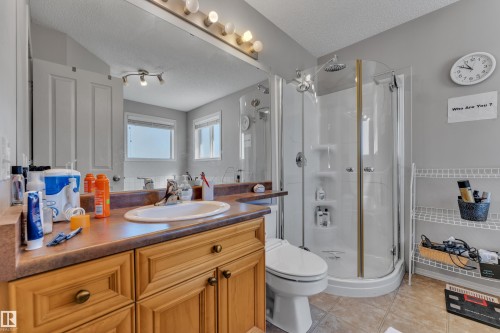 Bathroom with a wood-finish vanity, integrated oval sink, and a large mirror with strip lighting - 14031 136 Street, Edmonton, AB 