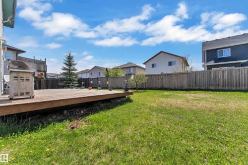 Expansive backyard featuring a large wooden deck, a manicured lawn, and a tall privacy fence - 14031 136 Street, Edmonton, AB 
