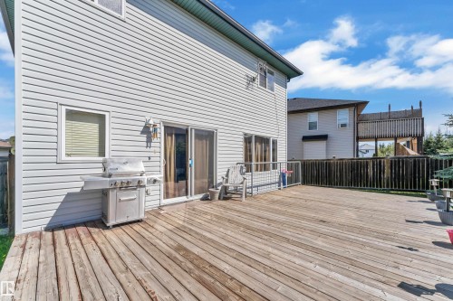 Expansive wood deck with a white vinyl-sided exterior and sliding glass patio doors - 14031 136 Street, Edmonton, AB 