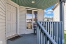 Covered front porch featuring a paneled entry door, siding exterior, and a protective railing system - 14031 136 Street, Edmonton, AB 