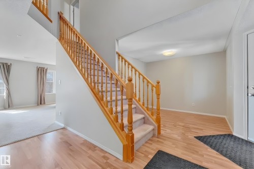 Two-story foyer featuring wood-finish flooring, a carpeted staircase with wood banisters, and light gray wall tones - 14031 136 Street, Edmonton, AB 