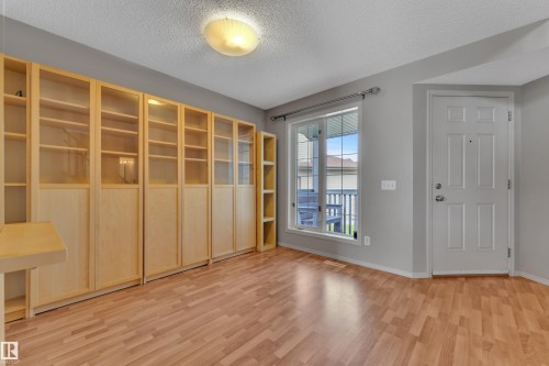 Light wood-finish flooring complemented by a series of built-in cabinetry featuring glass and solid panels - 14031 136 Street, Edmonton, AB 