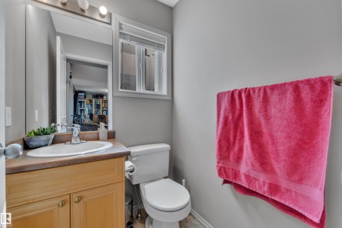 Bathroom featuring a wood-finish vanity with an integrated sink, a large mirror, and overhead lighting - 14031 136 Street, Edmonton, AB 
