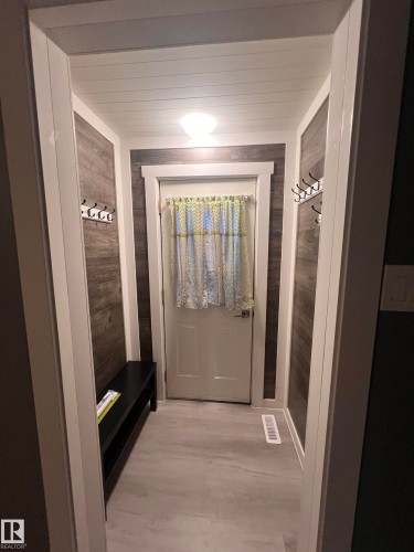 Entryway featuring wood-finish accent walls, light-toned flooring, and a white paneled door - 69 Railway Avenue, Star, AB 