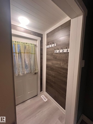 Entryway featuring light wood-finish flooring, dark wood-finish accent wall, and a white planked ceiling - 69 Railway Avenue, Star, AB 