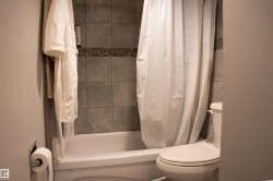 Tub and shower combination with full-height tile surround featuring a decorative mosaic accent band - 