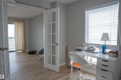 French doors opening to a space with wood-finish flooring and a balcony, complemented by a window with blinds - 1703 11027 87 Avenue N, Edmonton, AB - Indoor Photo Showing Office