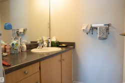 Bathroom vanity with a dark countertop and integrated sink, complemented by light wood-finish cabinetry - 