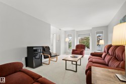Living area featuring light gray walls, white ceiling, and light-toned carpet flooring - 