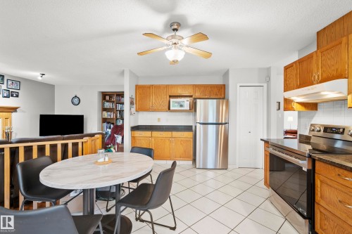 Kitchen featuring tile flooring, wood cabinetry, stainless steel refrigerator, and stainless steel range - 15503 62 Street, Edmonton, AB 