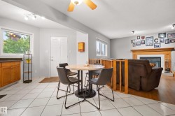 Bright open-concept space featuring white tile flooring, natural wood-finish cabinetry with dark countertops, and a white entry door - 