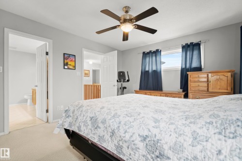Bedroom featuring a ceiling fan with integrated lighting, a window with dark curtains, and light-toned carpet - 15503 62 Street, Edmonton, AB 