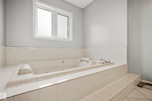 Built-in jetted tub with chrome fixtures, surrounded by white ceramic tile - 15503 62 Street, Edmonton, AB 