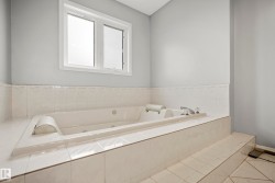 Built-in jetted tub with chrome fixtures, surrounded by white ceramic tile - 