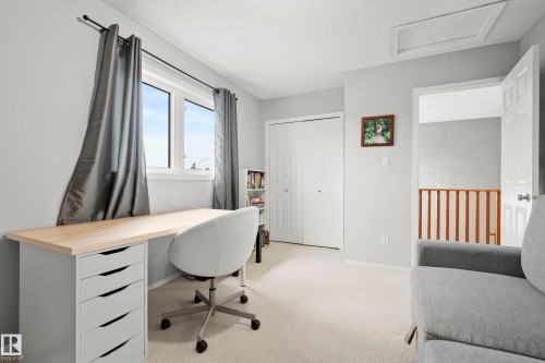 Neutral-toned room featuring a window with abundant natural light, light-colored carpeting, white bi-fold closet doors, and light gray painted walls - 15503 62 Street, Edmonton, AB 