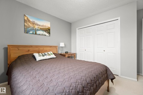 Bedroom featuring a light wood headboard, textured wall-to-wall carpeting, and neutral gray wall paint - 15503 62 Street, Edmonton, AB 