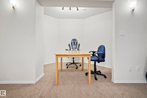 Carpeted interior space featuring white walls, white baseboards, and built-in wall sconces - 15503 62 Street, Edmonton, AB 