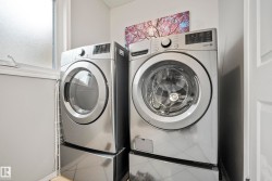 Dedicated laundry area featuring a front-loading washer and dryer, both in a stainless steel finish, set upon coordinating pedestals - 