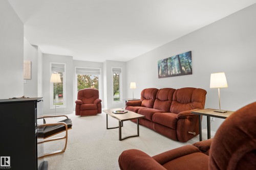 Living room featuring light-colored carpet flooring, multiple windows with blinds, and neutral wall tones - 15503 62 Street, Edmonton, AB 