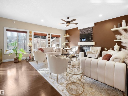 Spacious living area featuring wood-finish flooring, recessed lighting, fireplace, and a ceiling fan - 2019 Cameron Ravine Way Nw, Edmonton, AB 