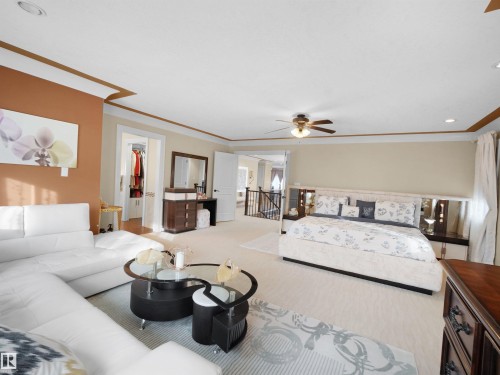 Spacious bedroom featuring carpet flooring, recessed lighting, a ceiling fan, crown molding, and a walk-in closet with built-in shelving - 2019 Cameron Ravine Way Nw, Edmonton, AB 